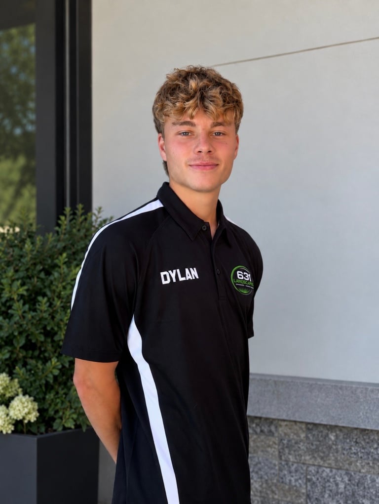 Portrait of a young man named Dylan wearing a black polo shirt with white stripes, standing outdoors against a light wall